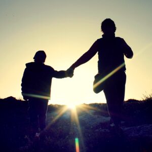 Image of a silhouetted parent and child holding hands in the sunset, representing how Harwood Legal helps divorcing parents understand the new WV child custody law regarding shared custody.
