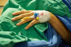 The hand of a person in a hospital bed represents the need to recover personal injury compensation in WV and the key role of evidence.