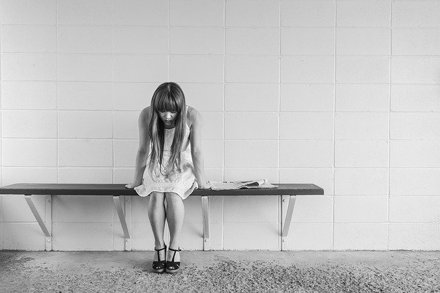 Image of woman on a bench grieving with head bowed, representing how Logan County, WV wrongful death lawyer Jason Harwood can help you obtain a wrongful death settlement.